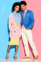 Young african amercian smiling girl and guy hugging on pink and blue background