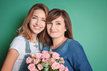 Attractive young woman with her mother on color background