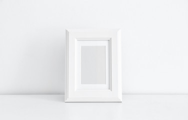 Empty frame on table near white wall