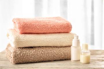 Obraz na płótnie Canvas Bath towels and cosmetics on table against light background