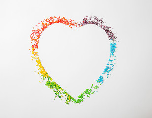 Many rainbow sprinkles in shape of heart on white background