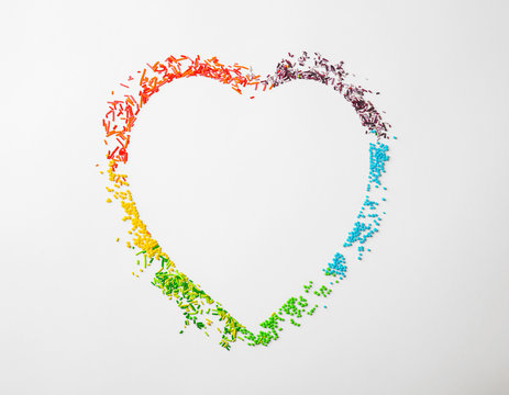 Many rainbow sprinkles in shape of heart on white background