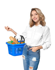 Young woman holding shopping basket with groceries on white background