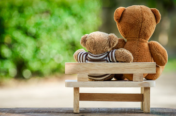 two bear dolls on wooden bench with dramatic tone