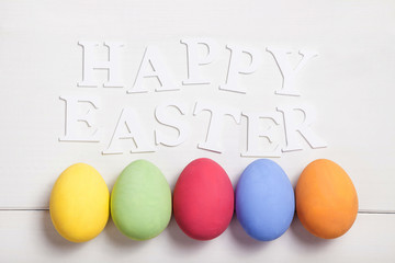 Easter composition with colored eggs on wooden white background