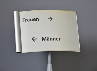 Schild in einem Amt. Frauen rechts und Männer links.