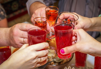 People drink at the table, clink glasses. Cheers
