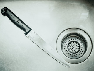 black handle stainless knife after clean and drop of water in silver color sink with murder , horror concept background