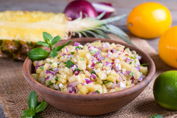 Pineapple salsa with lemon and lime in a ceramic bowl on a table