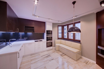 The combined white kitchen with dark inserts and a marble floor