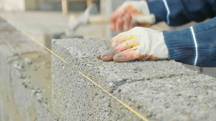 Fototapeta na wymiar Construction worker builds brick wall, closeup view at construction site
