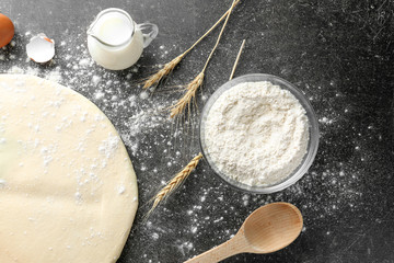 Raw dough with jug of milk on table