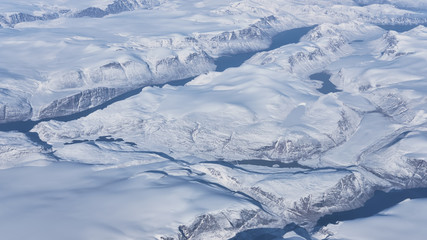 Fototapeta na wymiar Aerial view of the glaciers and icebergs of Greenland from the window of an airplane passing by