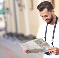 Handsome tourist on the street looking at a guide