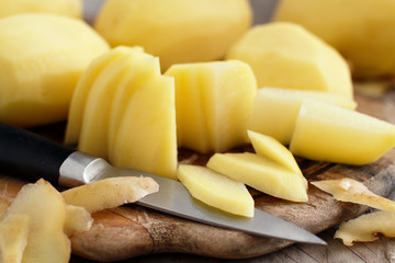 Raw peeled potatoes with a knife