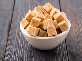 brown cane sugar in a white Cup on a brown wooden background, side view