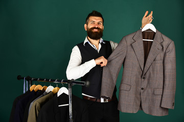 Designer presents jacket on clothes hanger. Man with beard