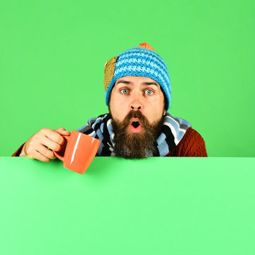 Hipster with beard and surprised face has tea or coffee