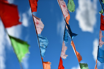 Colorful Prayer flags flying in wind with white clouds and blue sky in Inner Mongolia