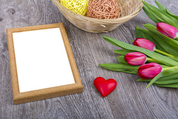 Picture frame, heart and tulips on a wooden desk