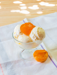 Vanilla ice cream scoops with homemade apricot jam in glass bowl. Selective focus