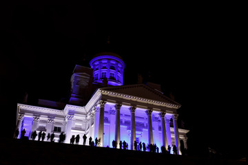 People stant in front of illuminated Helsinki St Nicholas cathed