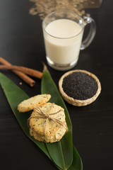 Sesame Cookies, sesame and milk on black wooden background