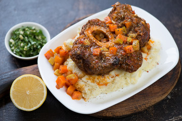 Osso buco made of cross cut veal shank and served on mashed potato, selective focus, studio shot