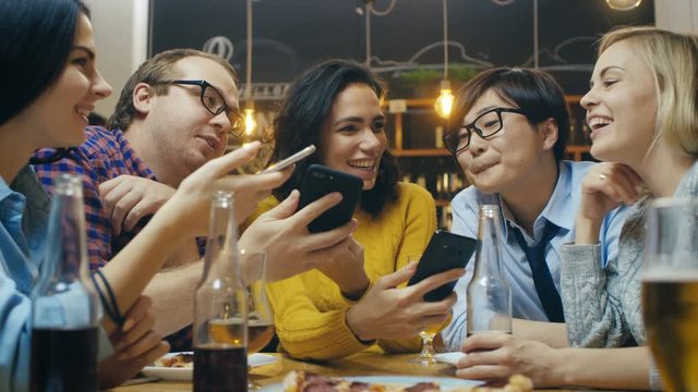 In the Bar/ Restaurant Diverse Group of Friends Have Good Time Sharing Pictures and Whatnot with Their Smartphones. Shot on RED EPIC-W 8K Helium Cinema Camera.
