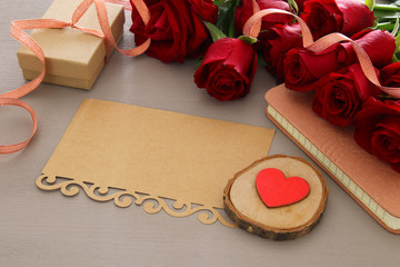 Valentine's day background. Beautiful bouquet of roses next to empty letter on wooden table.