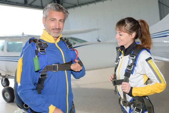 Male and female sky divers preparing their harnesses