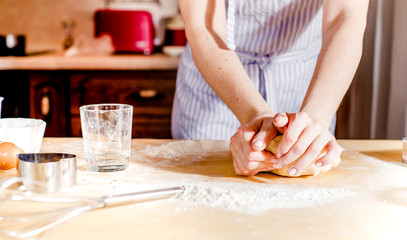 Obraz na płótnie Canvas Woman's hands knead dough on a table, for the holiday
