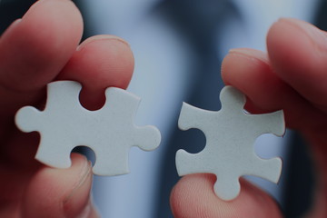 Businessman holding two blank white puzzle pieces in his hands conceptual of solving a problem, growth and development.