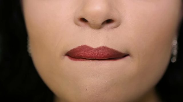 Woman licks his lips with red lipstick