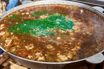 The process of making soup from lamb - shurpa in a cauldron in the open air.