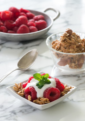 raspberry granola yogurt parfait marble spoon bowl table