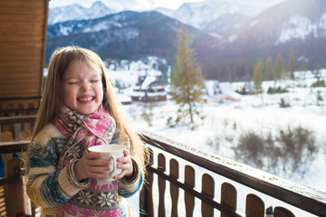 portrait of a little girl with a cup of tea on the background of winter mountains, Zakopane, Koscielisko. Concept of winter holidays and winter vacations
