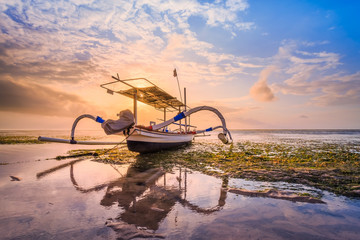 Fototapeta na wymiar Traditional Balinese fisherman boat with sunrise sky as background