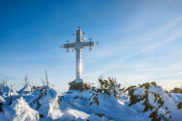 christian cross on snow-covered mountain at sunny morning