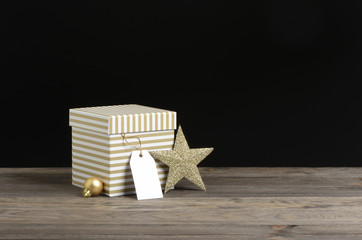 Caja para regalos de rayas doradas y blancas sobre fondo de madera y negro