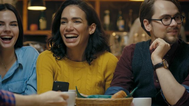 Beautiful Hispanic Woman Shows Interesting Stuff on Her Smartphone to Her Friends while They Have Good Time in Bar. Shot on RED EPIC-W 8K Helium Cinema Camera.
