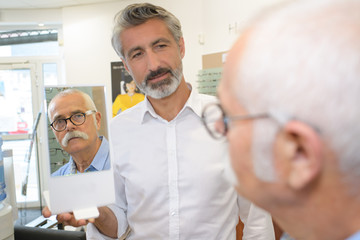 Obraz premium Optician holding mirror for customer to assess eyeglasses