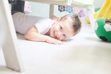 Little smiling boy is lying on a floor at home.