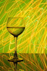 a glass of white wine on a blurred colored background