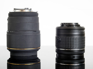 DSLR camera lenses on top of a glass reflective surface and white background