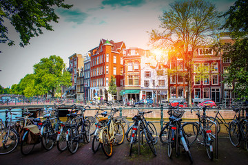 Amsterdam. Parking for bicycles on background of old city at sunset in capital of Netherlands. Streets for walks in Amsterdam. - obrazy, fototapety, plakaty