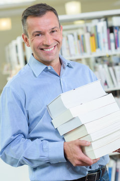 man carrying a pile of books