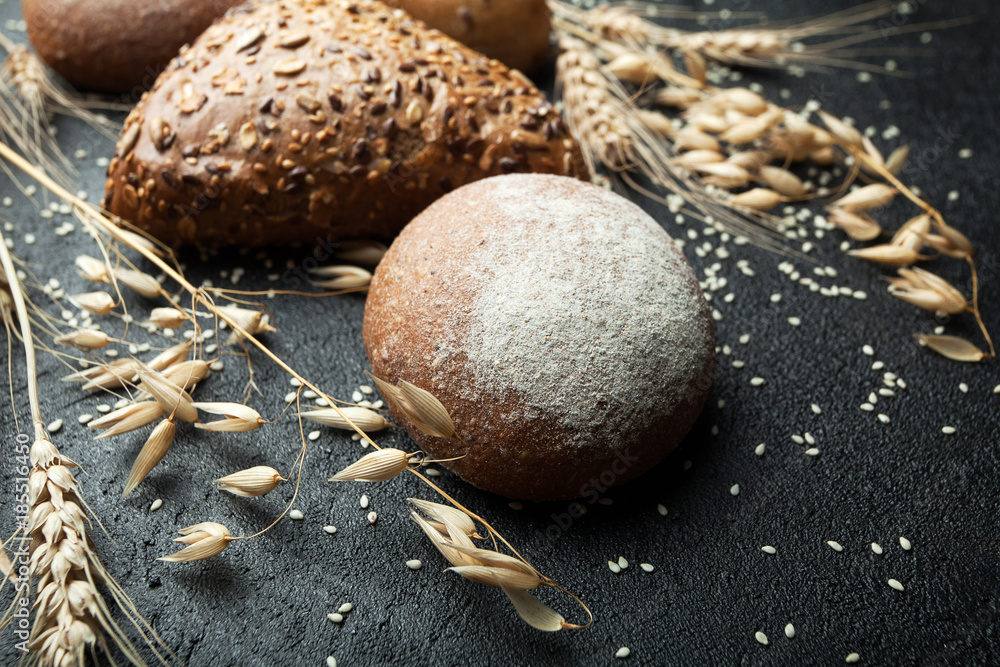 Poster black bread on a rustic background with spikelets of wheat and oats.