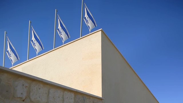 Four flags of Israel flapping in wind at top of the building