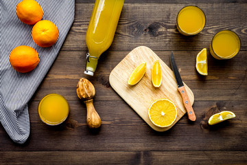 Healthy vitamin drink. Fresh orange juice near fruits and juicer on dark wooden background top view